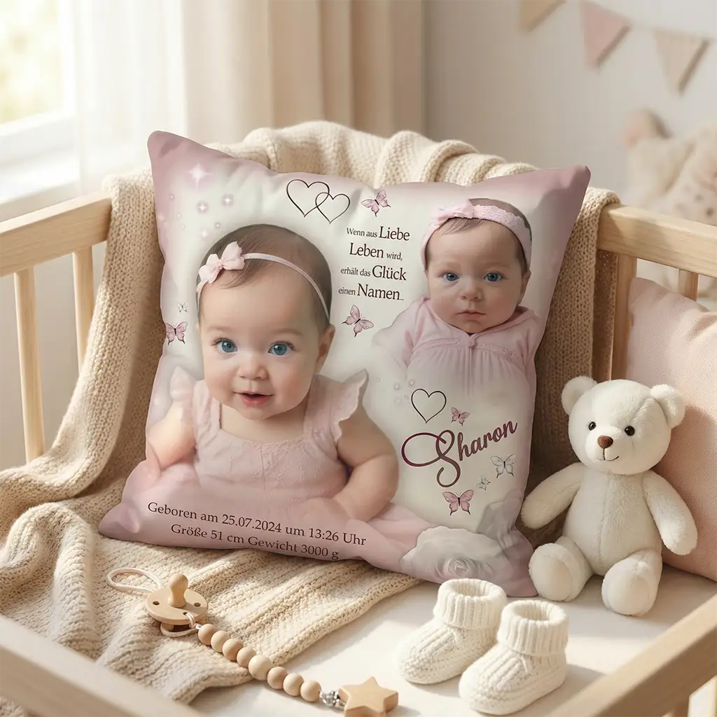 Personalisiertes Babykissen mit Fotos eines Mädchens, Name „Sharon“, Geburtsdatum, Größe und Gewicht, rosa Schmetterlingen und Herzen – dekoriert im Babybett mit Stoffbär, Strickschühchen und Holzspielzeug als Geschenk zur Geburt.