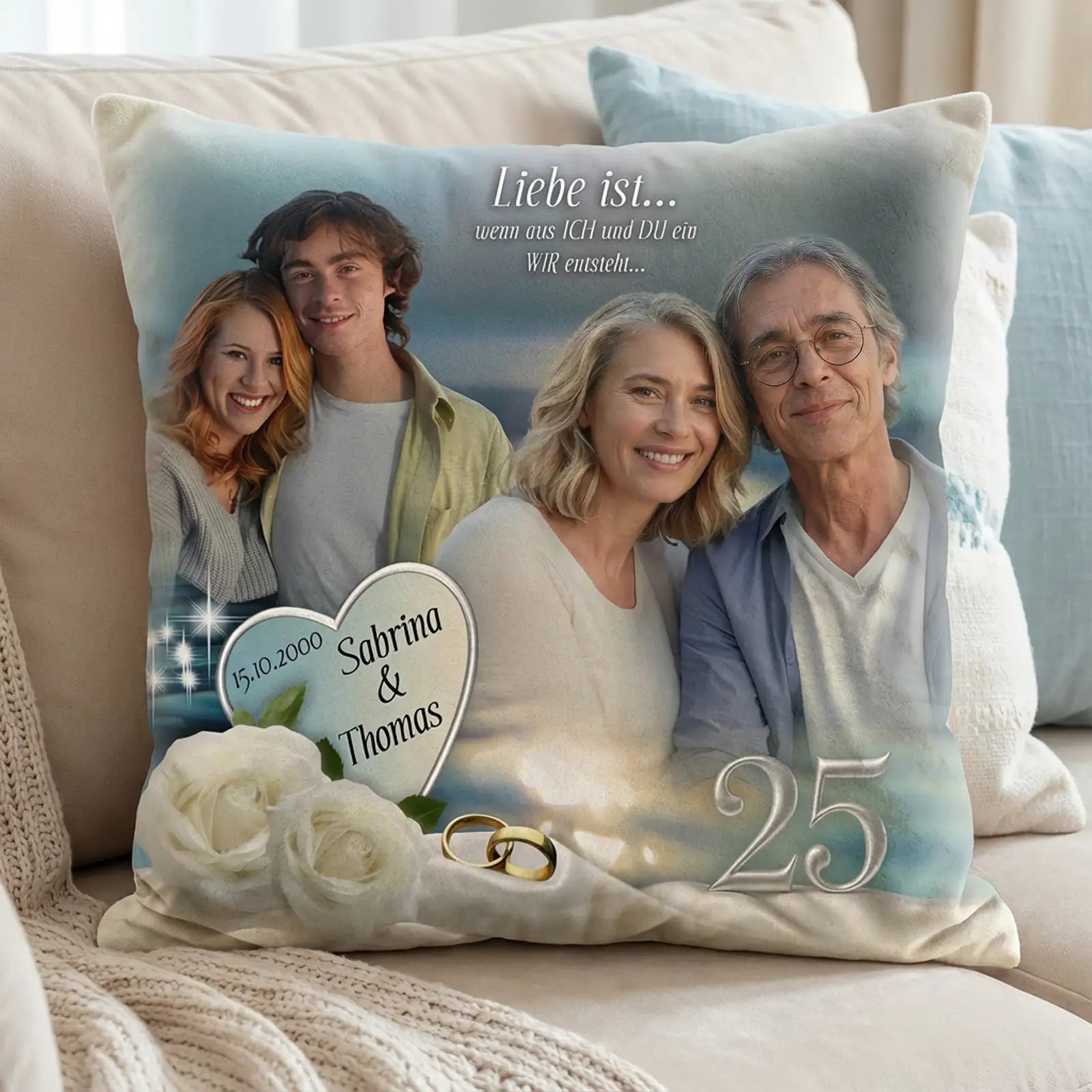 Personalisiertes Fotokissen zur Silberhochzeit mit Familienporträt, Herzmotiv mit Namen Sabrina und Thomas, Datum 15.10.2000, Zahl 25, weißen Rosen und Eheringen, arrangiert auf hellem Sofa im wohnlichen Ambiente