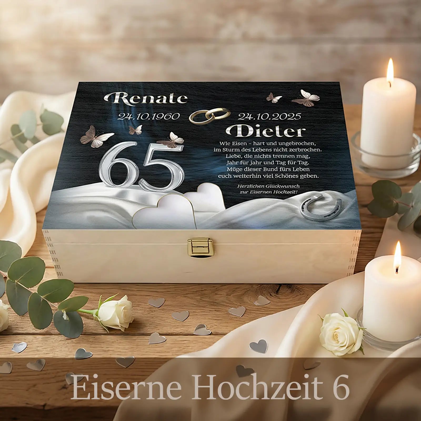 Personalisierte Holzbox zur Eisernen Hochzeit mit hellem Holz und Metallverschluss. Auf dem dunklen Deckel stehen die Namen Renate und Dieter mit Jubiläumsdatum, die Zahl 65, zwei Eheringe und Schmetterlinge. Die Box ist dekoriert mit Kerzen, weißen Rosen, Stoff und Herzkonfetti und symbolisiert 65 Jahre Ehe und Verbundenheit.
