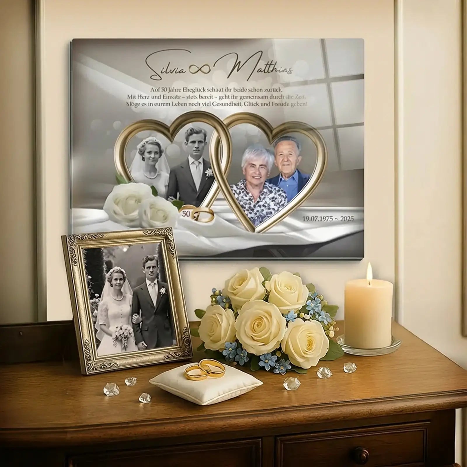 Acrylglas zur Goldenen Hochzeit mit personalisiertem Fotomotiv an der Wand über einer Kommode: links Hochzeitsfoto eines jungen Brautpaares, rechts aktuelles Porträt desselben Ehepaares nach 50 Ehejahren, eingefasst in Herzformen, mit den Namen Silvia und Matthias, goldenen Eheringen, weißen Rosen, Kerze und zusätzlichem gerahmtem Hochzeitsfoto als dekoratives Arrangement in einem ruhigen, eleganten Wohnraum.