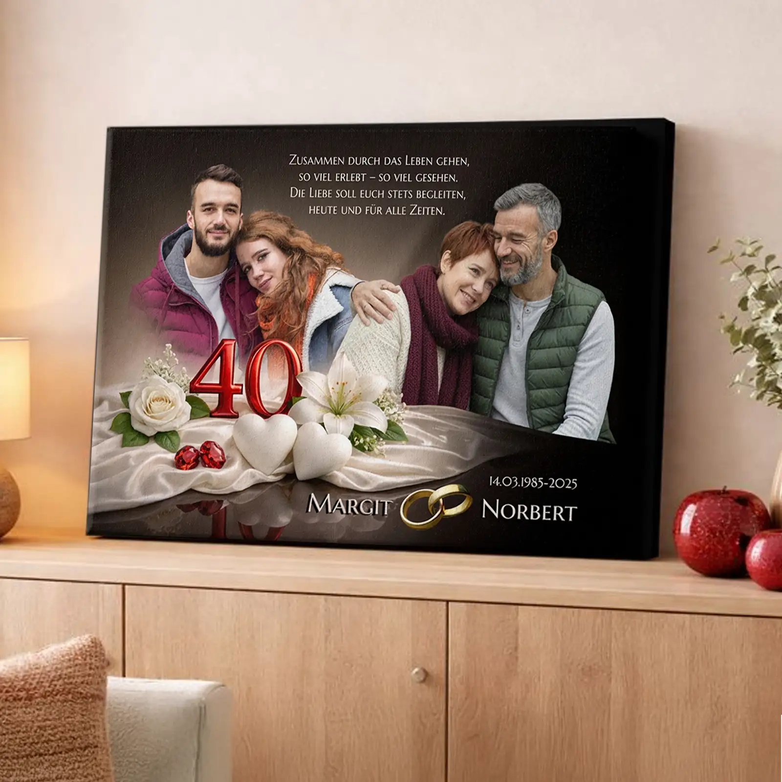 Personalisierte Fotoleinwand zur Rubinhochzeit (40 Jahre) mit großem Fotodruck eines Ehepaares und zwei Bildern aus unterschiedlichen Lebensphasen. Auf der Leinwand sind die Jubiläumszahl 40, ein Glückwunschtext, weiße Blumen, Herzmotive und goldene Trauringe zu sehen. Die Leinwand steht auf einem Sideboard in einem Wohnzimmer. Geschenkidee zum 40. Hochzeitstag.