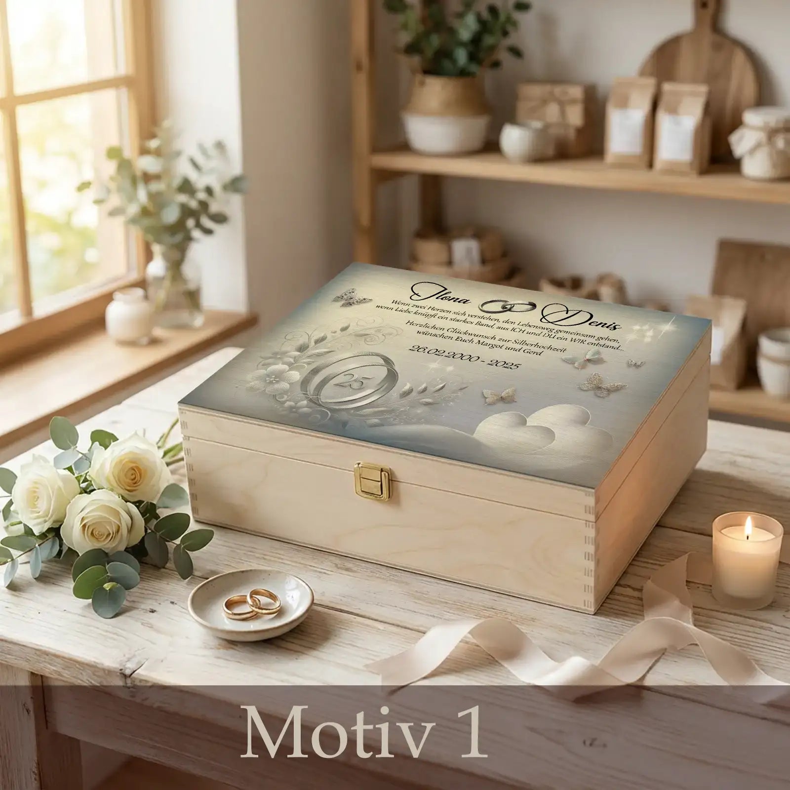 Personalisierte Holzbox zur Silberhochzeit mit Namen des Ehepaares, Datum und Herzmotiv, arrangiert auf Holztisch mit Eheringen, weißen Rosen, Kerze und Schleifenband.