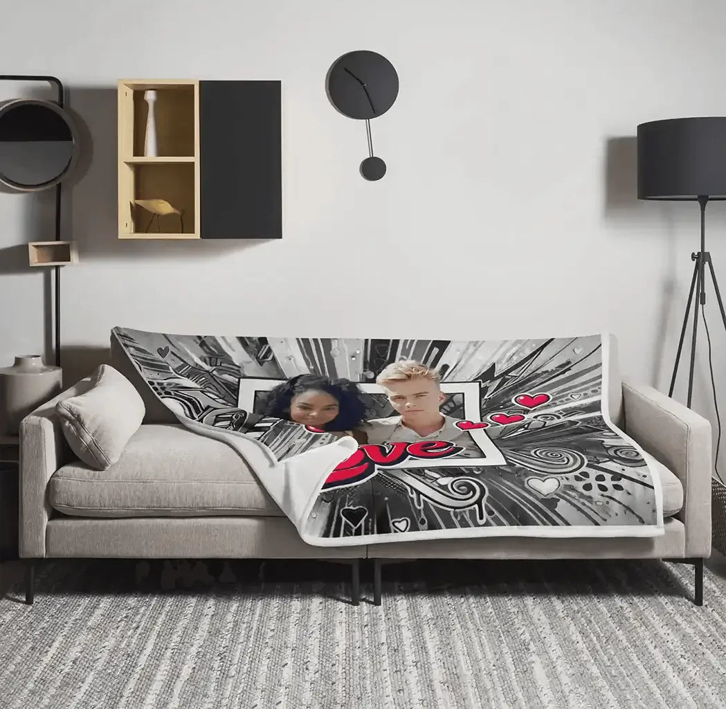 Personalisierte Kuscheldecke mit Paarfoto, Herzmotiven und Love-Schriftzug auf grauem Sofa