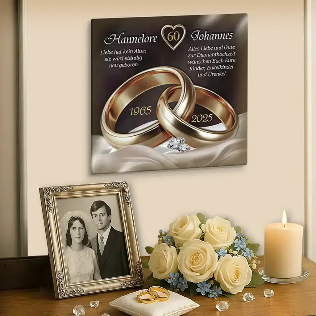 Leinwand zur Diamanthochzeit mit goldenen Ringen, Rosen, Kerze und Hochzeitsfoto auf Kommode.