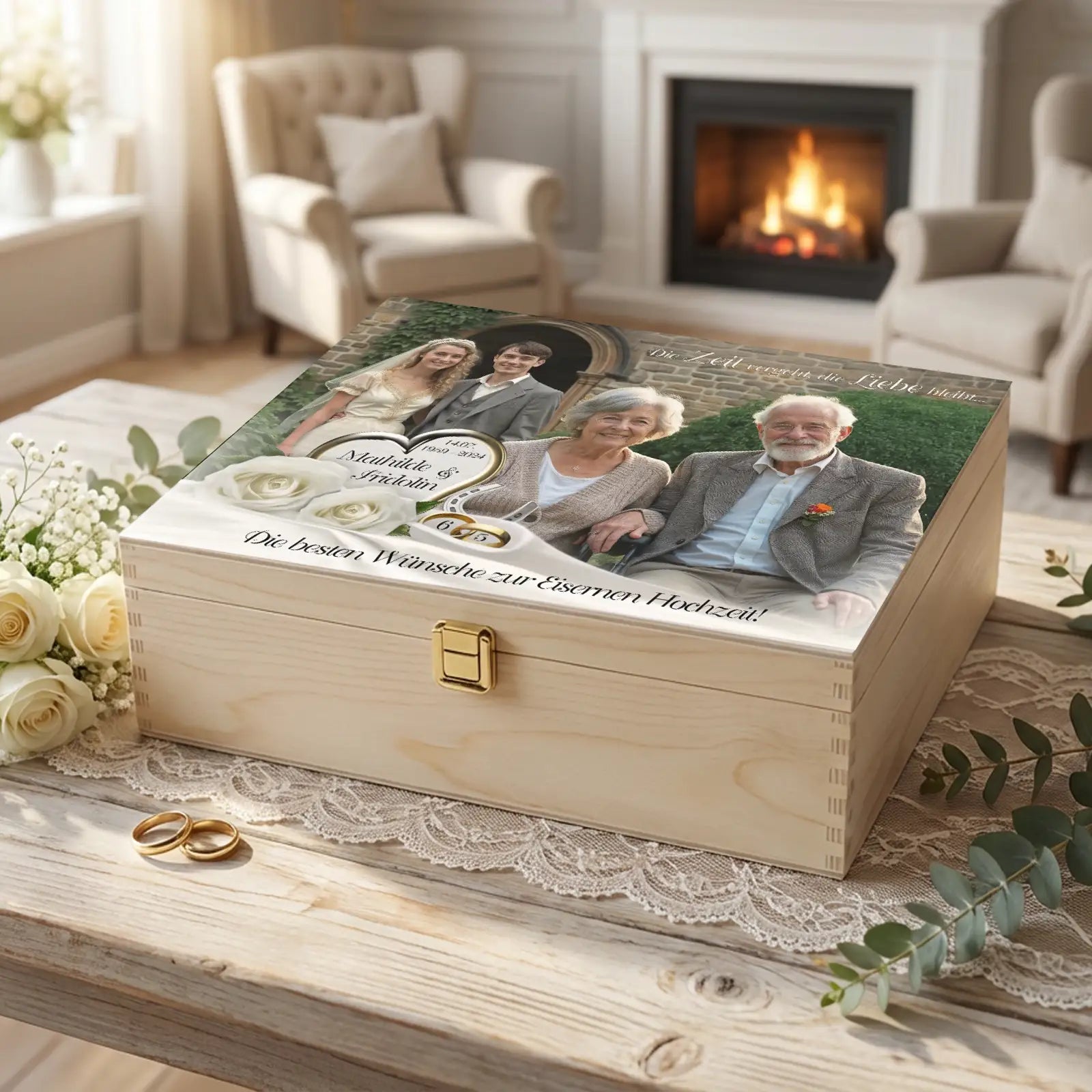 Personalisierte Holzbox zur Eisernen Hochzeit mit Fotomotiv eines älteren Ehepaares, Hochzeitsbild von früher und heute, Zahl 65, weiße Rosen und Eheringe, arrangiert in gemütlichem Wohnzimmer mit Kamin