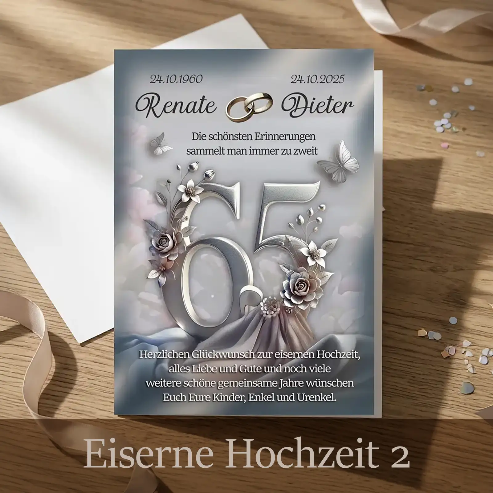 Personalisierte Glückwunschkarte zur Eisernen Hochzeit in elegantem Grau-Silber: Die große Zahl 65 steht im Mittelpunkt, verziert mit floralen Ornamenten und Schmetterlingen. Oben sind die Namen Renate und Dieter mit Jubiläumsdaten zu sehen. Die Karte liegt auf einem Holztisch neben Umschlag, Band und Streudeko und wirkt ruhig, wertig und zeitlos.