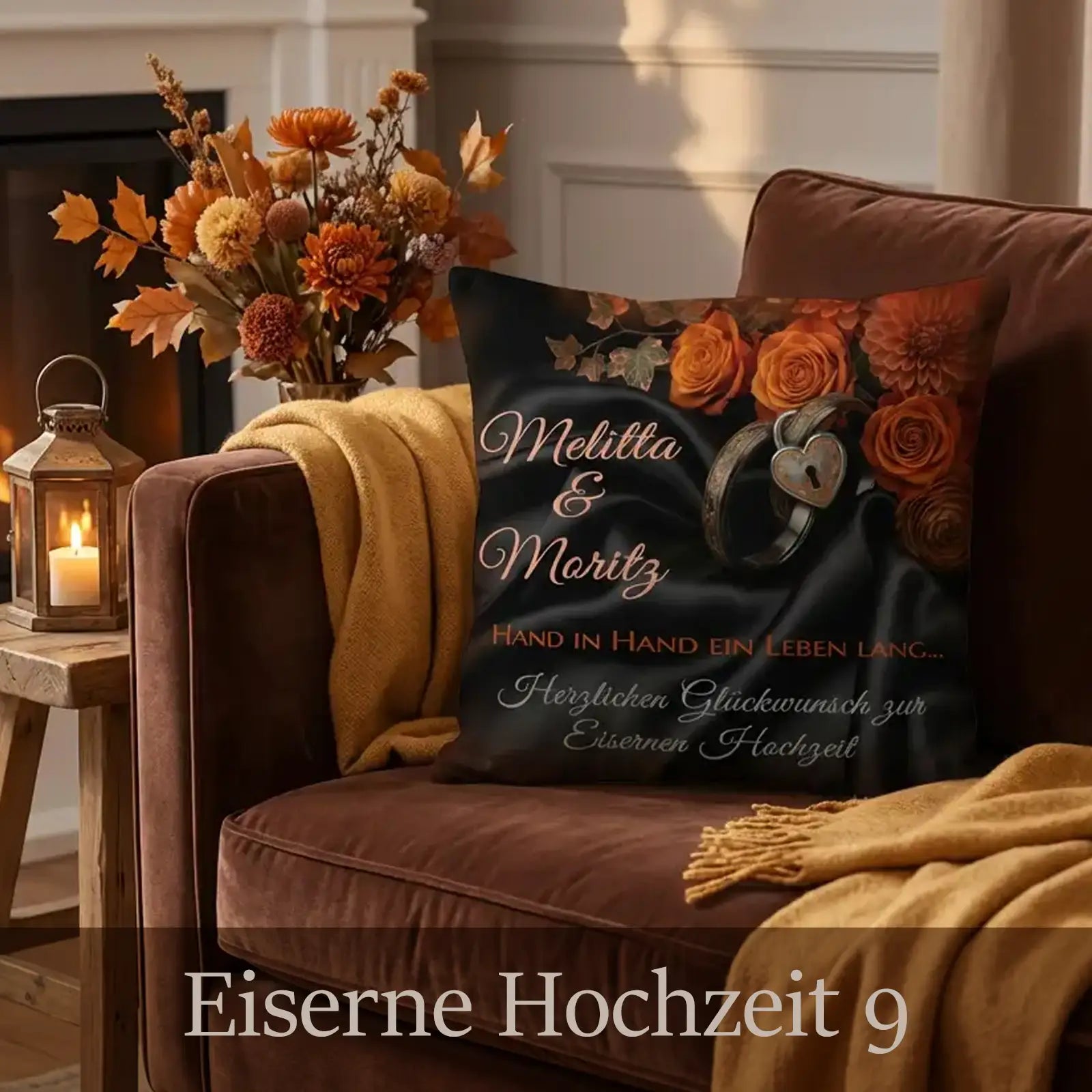 Kissen zur Eisernen Hochzeit mit dunklem Hintergrund, herbstlichen Rosen in Orange- und Kupfertönen, Ringmotiv mit Herz, personalisierten Namen Melitta und Moritz sowie Glückwunschtext, arrangiert auf braunem Sessel mit Decke, Laterne und herbstlichem Wohnzimmer-Ambiente