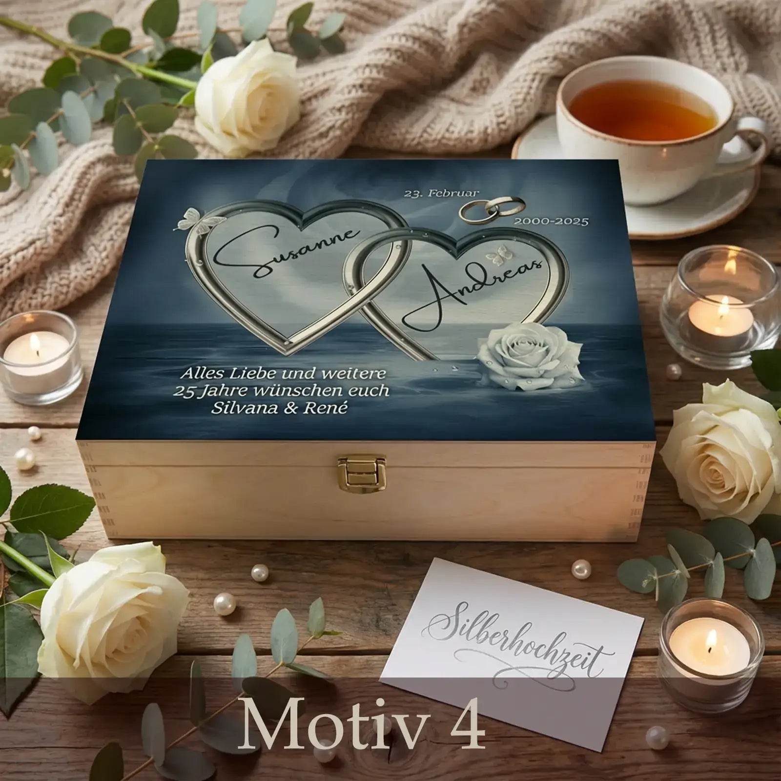 Personalisierte Holzbox zur Silberhochzeit mit zwei ineinander verschlungenen silbernen Herzen, Namen des Paares und Gravur zum 25. Hochzeitstag, arrangiert mit weißen Rosen, Kerzen und Silberhochzeit-Karte auf Holztisch.