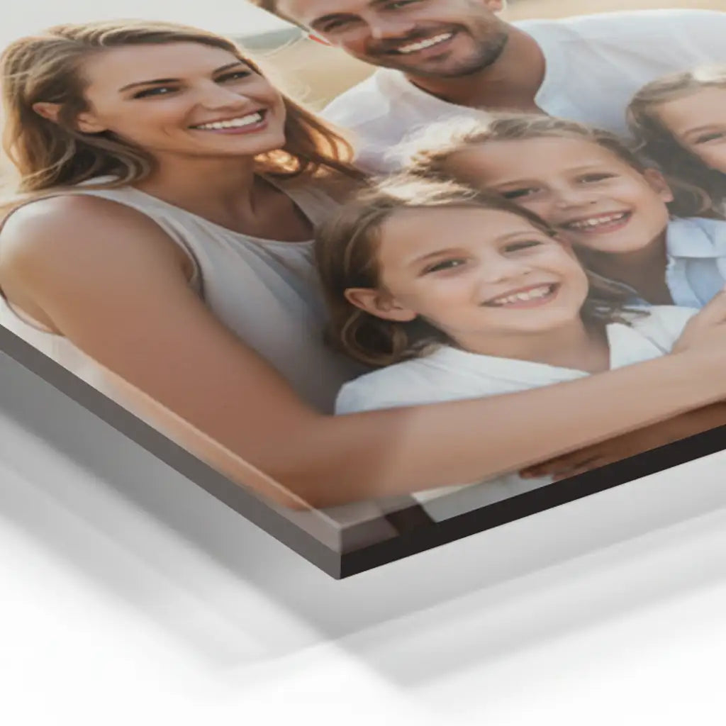 Detailansicht eines Acrylglas-Fotoprodukts mit Familienporträt: lächelnde Eltern mit zwei Kindern, nah aufgenommen, sichtbar glänzende Acrylglasoberfläche mit klaren Kanten und moderner Tiefenwirkung vor hellem Hintergrund.